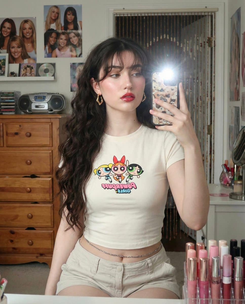 A young woman taking a mirror selfie with very long voluminous dark waves and...